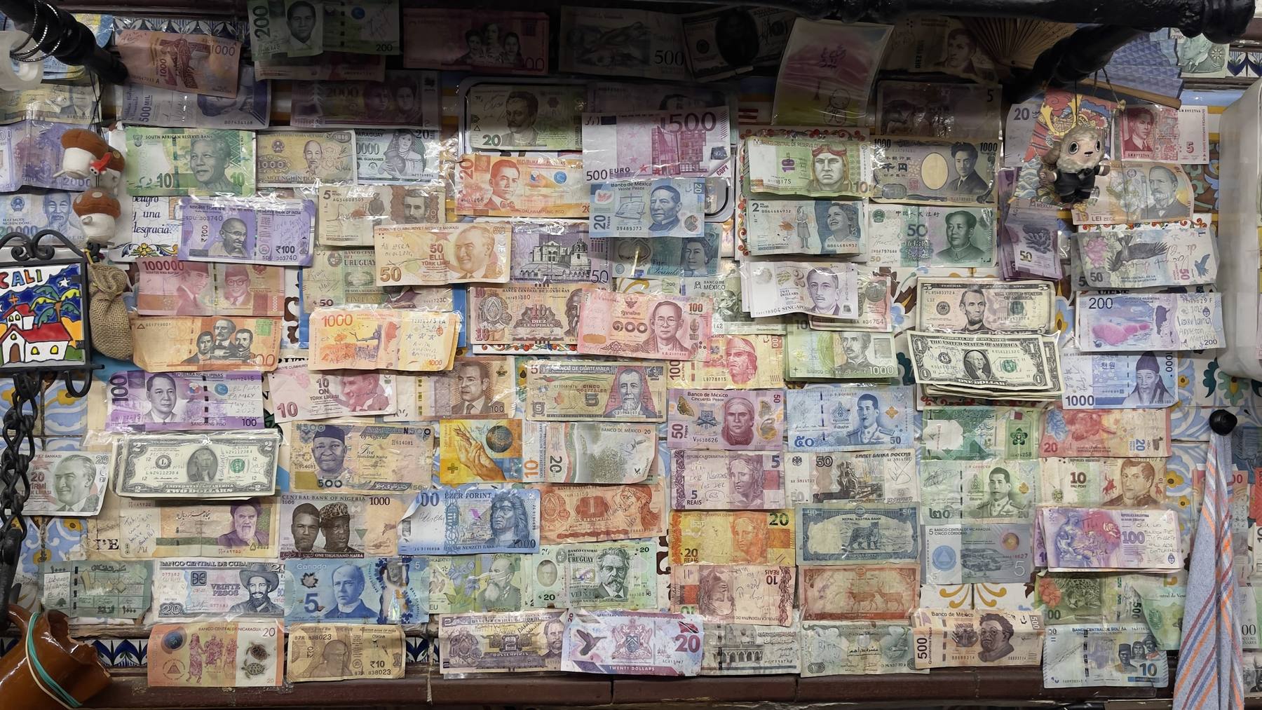 Pared del mesón cubierta de billetes de países de todo el mundo